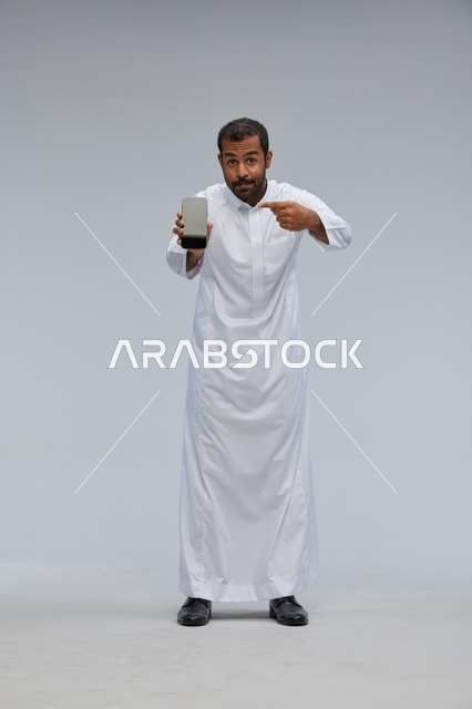 Saudi Man in White Thobe Pointing at Smartphone Screen