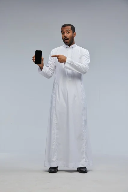 Saudi Man in White Thobe Pointing at Smartphone Screen