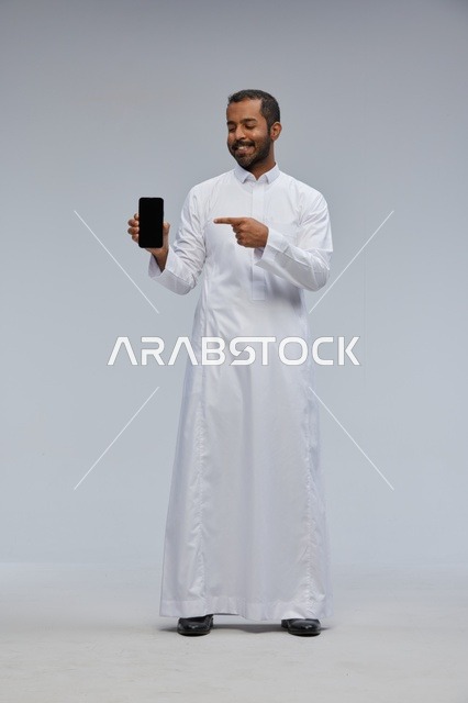 Saudi Man in White Thobe Pointing at Smartphone Screen