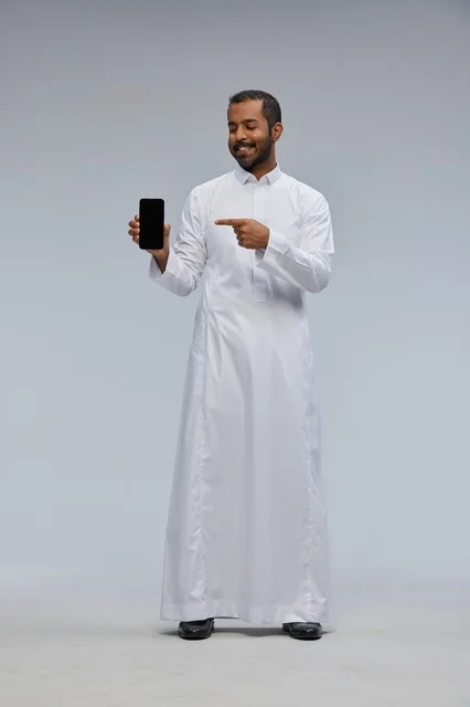 Saudi Man in White Thobe Pointing at Smartphone Screen