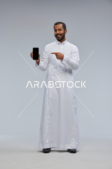Saudi Man in White Thobe Pointing at Smartphone Screen