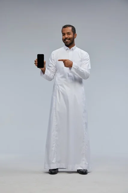 Saudi Man in White Thobe Pointing at Smartphone