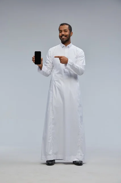 Saudi Man in White Thobe Pointing at Smartphone