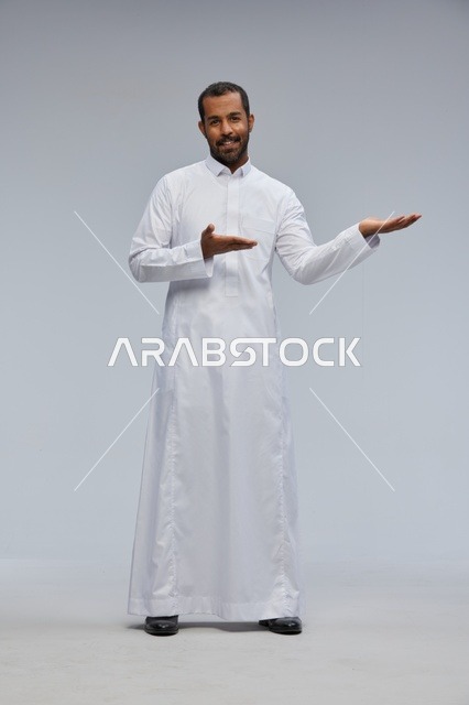 رجل سعودي يرتدي الثوب التقليدي يشير إلى مساحة عرض