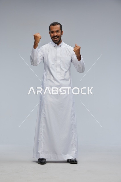 رجل سعودي يرتدي الثوب التقليدي الأبيض يحتفل بالنجاح والفوز