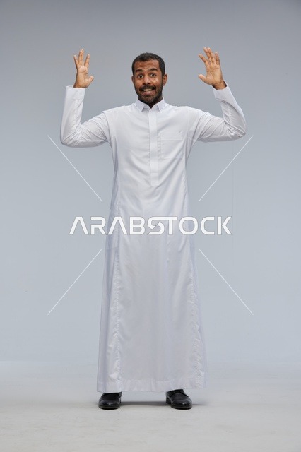 رجل سعودي بالثوب الأبيض يرفع يديه بتعابير مندهشة