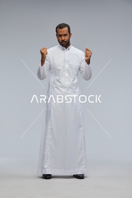 Saudi Man in White Thobe Clenching Fists Studio Portrait