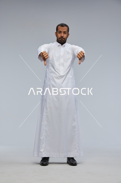 رجل سعودي بالثوب الأبيض يشير بإبهامه للأسفل رفضاً