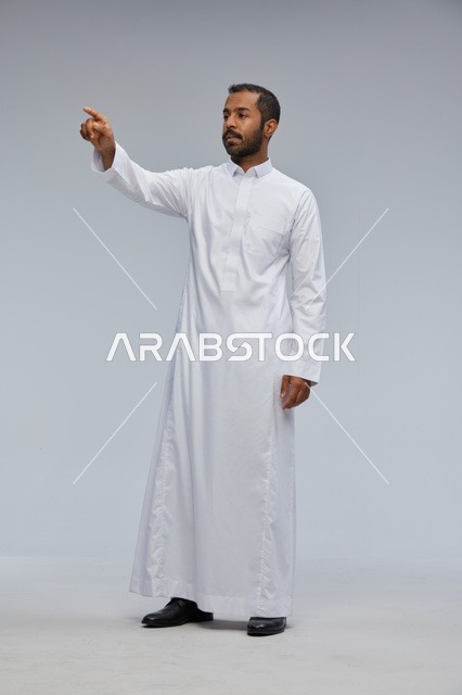 رجل سعودي يرتدي الثوب الأبيض يشير بإصبعه في الاستوديو
