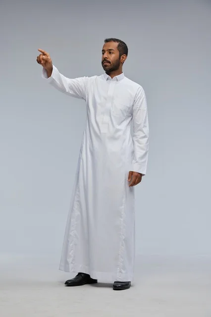 رجل سعودي يرتدي الثوب الأبيض يشير بإصبعه في الاستوديو