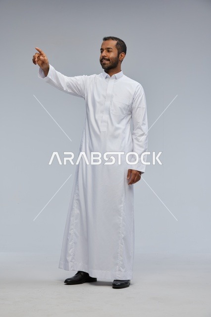 رجل سعودي يرتدي الثوب الأبيض يشير بإصبعه في الاستوديو