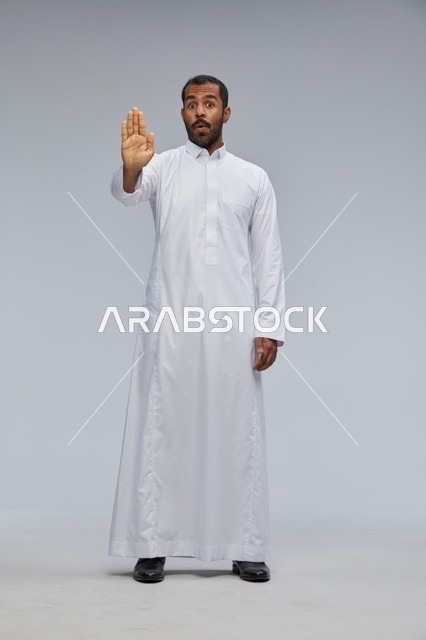 رجل سعودي بالثوب الأبيض يشير بعلامة التوقف في الاستوديو