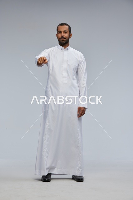 رجل سعودي بالثوب الأبيض يشير للكاميرا في الاستوديو