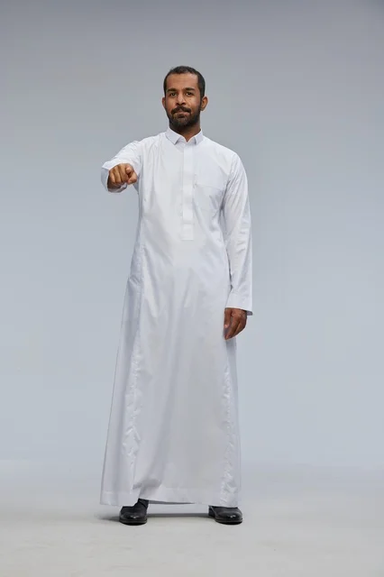 رجل سعودي بالثوب الأبيض يشير للكاميرا في الاستوديو