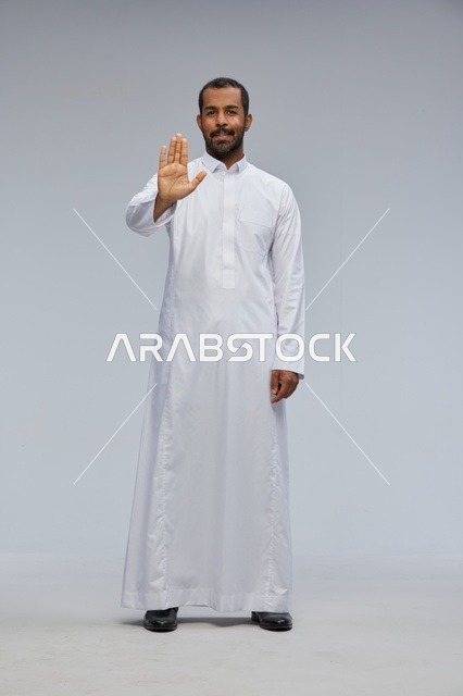 رجل سعودي بالثوب الأبيض يقوم بإشارة التوقف بيده