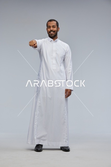 Smiling Saudi Man in White Thobe Pointing at Camera