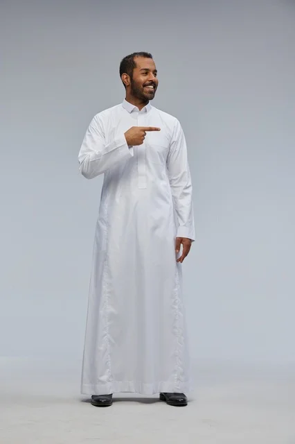 Saudi Man in White Thobe Pointing Against Grey Background