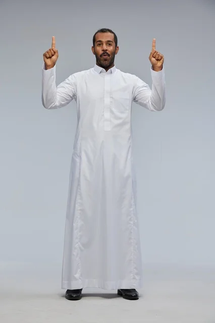 رجل سعودي بالثوب الأبيض يشير للأعلى في الاستوديو