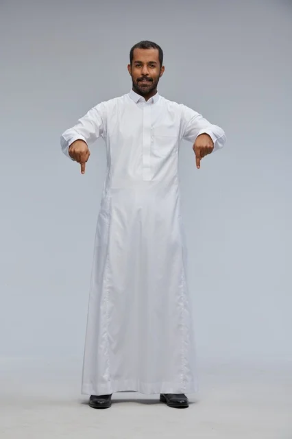 رجل سعودي يرتدي الثوب الأبيض يشير للأسفل في الاستوديو