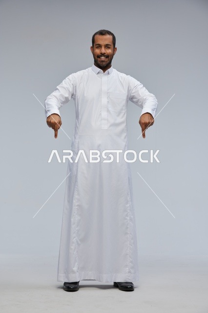 Saudi Man in White Thobe Pointing Down on Grey Background