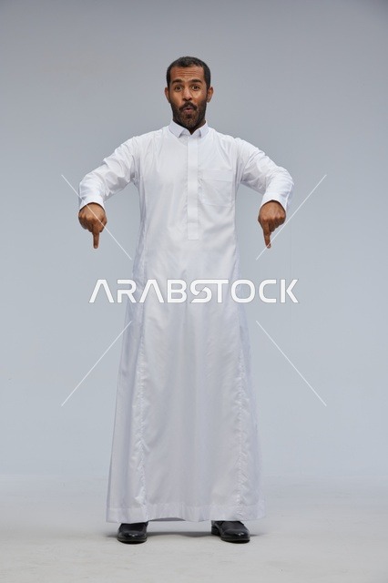 رجل سعودي بالثوب الأبيض يشير للأسفل في الاستوديو
