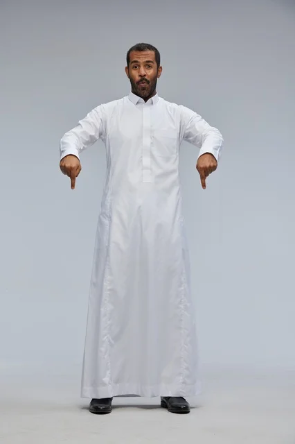 رجل سعودي بالثوب الأبيض يشير للأسفل في الاستوديو