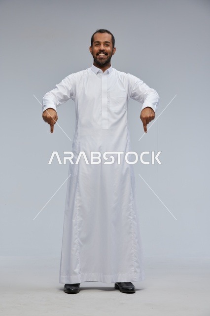 رجل سعودي بالثوب الأبيض يشير للأسفل في الاستوديو