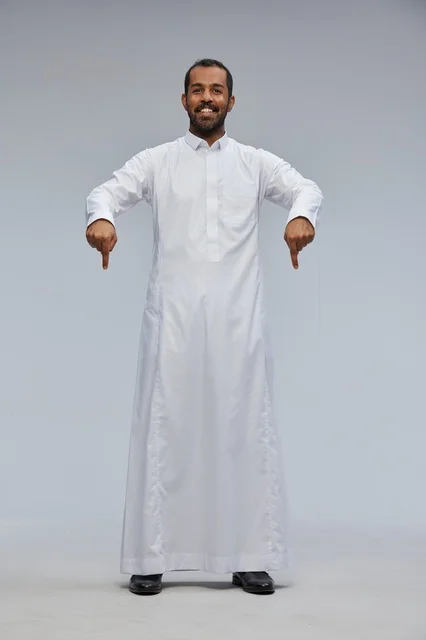 رجل سعودي بالثوب الأبيض يشير للأسفل في الاستوديو
