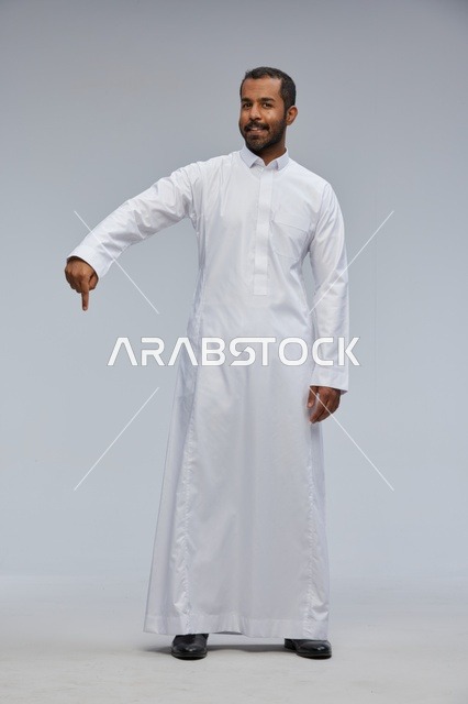 Saudi Man in White Thobe Pointing Down Studio Portrait