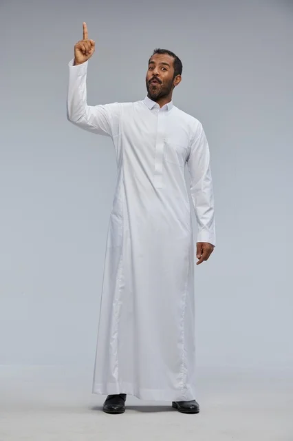 رجل سعودي بالثوب الأبيض يشير للأعلى في استوديو