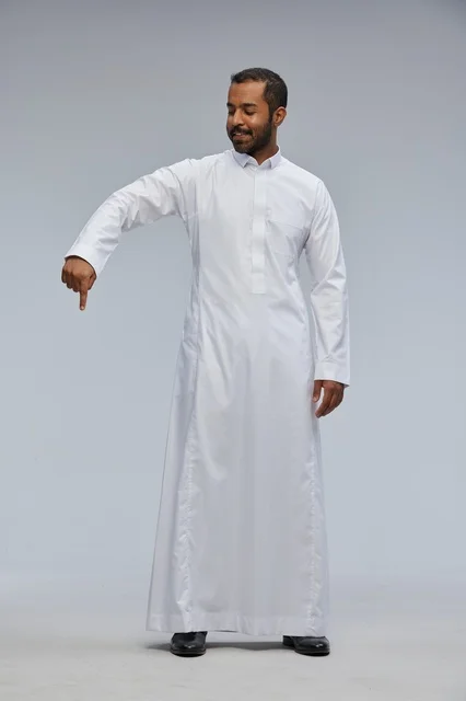رجل سعودي بالثوب الأبيض يشير للأسفل في خلفية استوديو