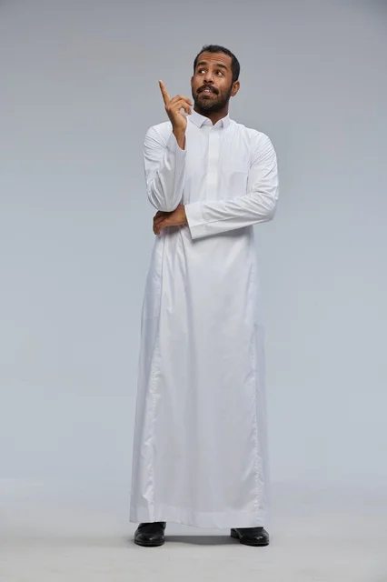 رجل سعودي بالثوب الأبيض يشير للأعلى بخلفية رمادية