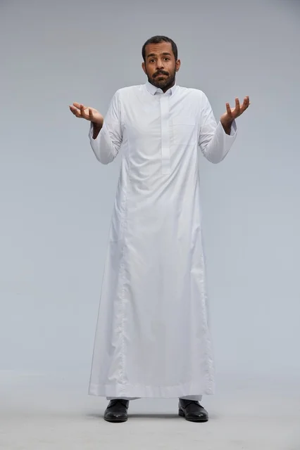 رجل سعودي بالثوب الأبيض يرفع يديه بتعبير الحيرة في استوديو
