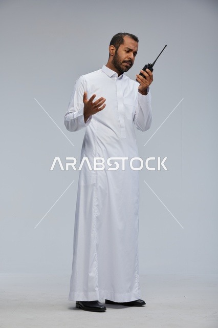 Saudi Man in White Thobe Using Handheld Radio