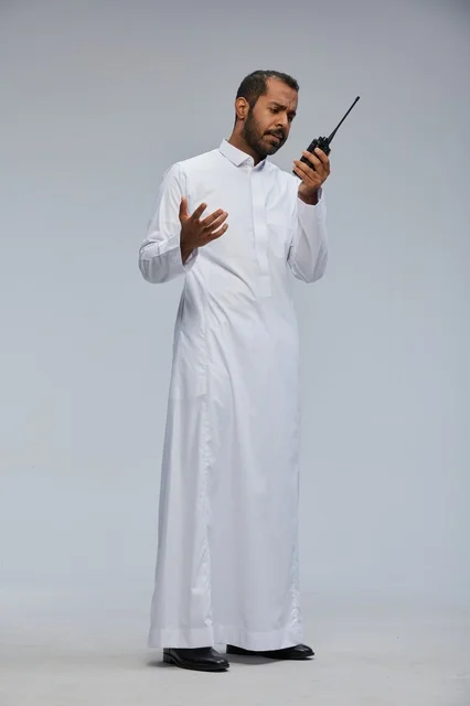 Saudi Man in White Thobe Using Handheld Radio