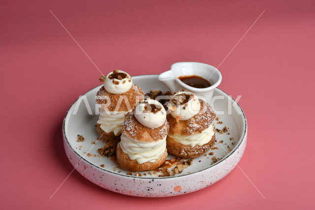 طبق من الحلا البارد مزين بالكريمة وجانبه صوص الشوكولاته ، حلا شرقي ، حلويات رمضانية ، حلويات وسكريات ، قطع الحلوى الشهية ، التحلاية ، حلويات باردة لذيذة