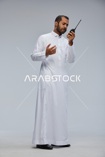 Saudi Man in White Thobe Using Walkie-Talkie Radio