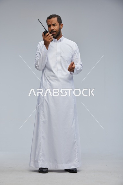 رجل سعودي بالثوب الأبيض يستخدم جهاز لاسلكي