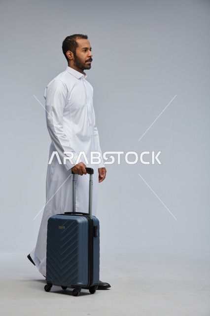 Saudi Man in White Thobe Walking with Blue Suitcase