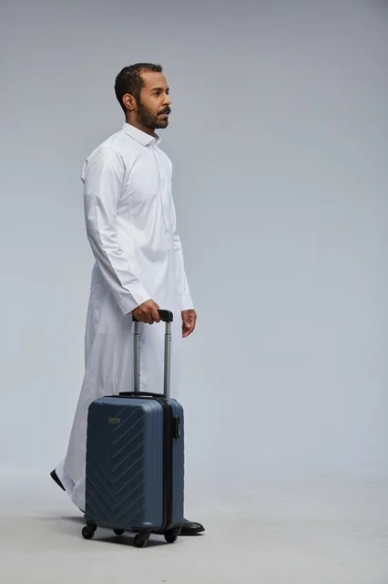 Saudi Man in White Thobe Walking with Blue Suitcase