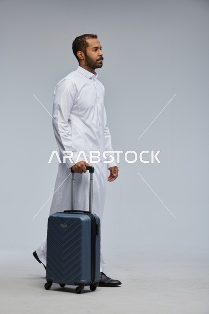 Saudi Man in White Thobe Walking with Blue Suitcase