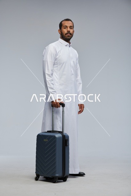 رجل سعودي يحمل حقيبة سفر بالثوب الأبيض في الاستوديو
