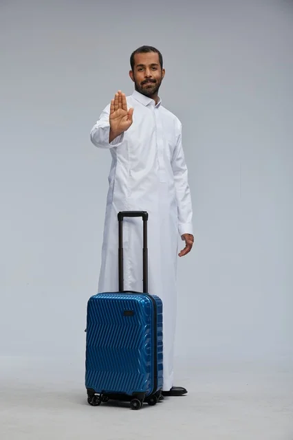 رجل سعودي مع حقيبة سفر يشير بعلامة التوقف