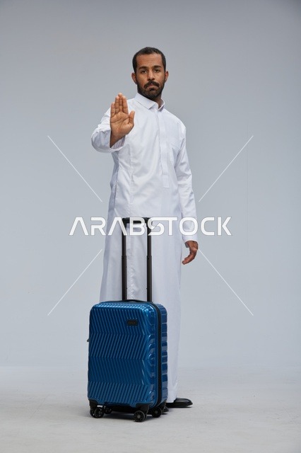 Saudi Man in Thobe with Blue Suitcase Making Stop Gesture