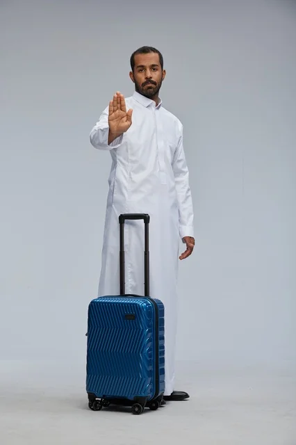 Saudi Man in Thobe with Blue Suitcase Making Stop Gesture