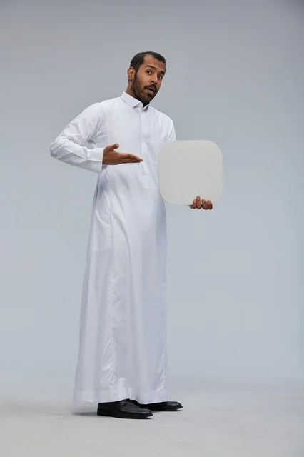 رجل سعودي يرتدي الثوب التقليدي يحمل لوحة بيضاء فارغة