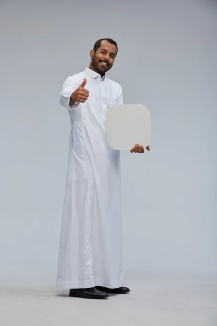 رجل سعودي يحمل لوحة فارغة مع إيماءة الإبهام للأعلى