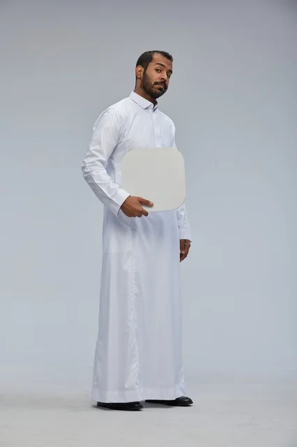 رجل سعودي يرتدي الثوب ويحمل لوحة بيضاء فارغة