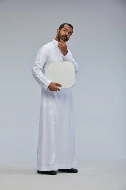 رجل سعودي بالثوب التقليدي يحمل لوحة فارغة بتعبير تفكير