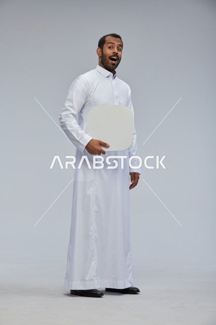 رجل سعودي يحمل لوحة بيضاء فارغة بتعبير مندهش